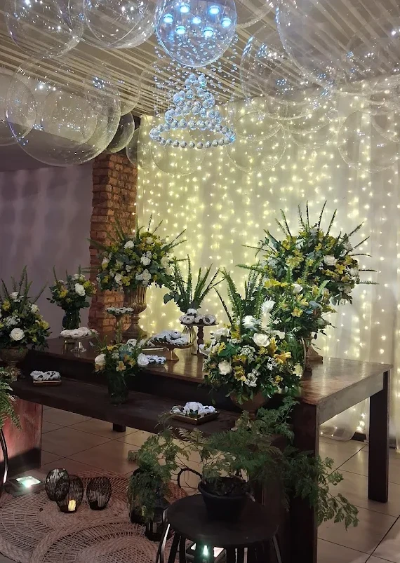 Mesa de doces decorada com flores e cortina de luzes